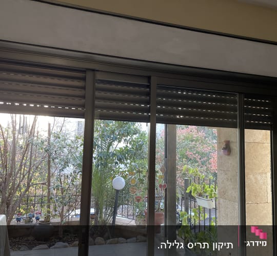 תריסים חומים סגורים חלקית על חלון זכוכית גדול